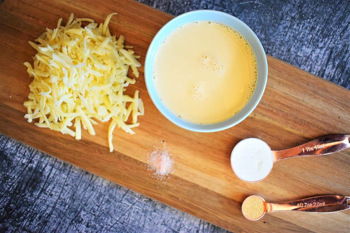 Nacho cheese sauce ingredients on wooden platter, blue background.