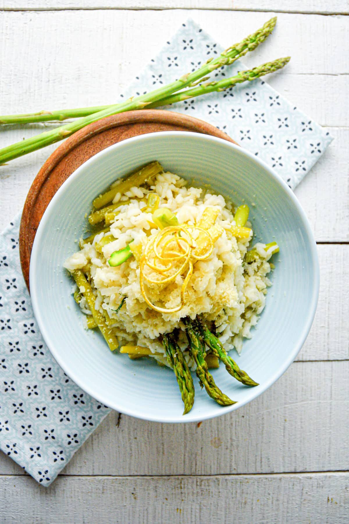 Risotto with lemon and asparagus in light blue bowl.