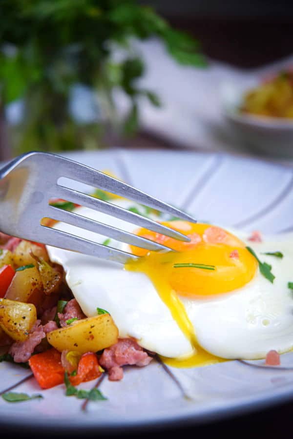 Electric skillet sausage and egg breakfast hash on a plate, dark background.