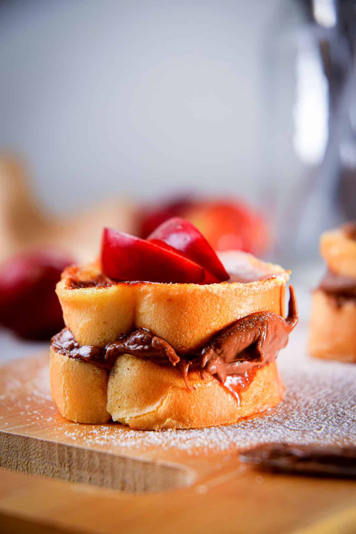 French toast stuffed with Nutella and topped with apples on cutting board.