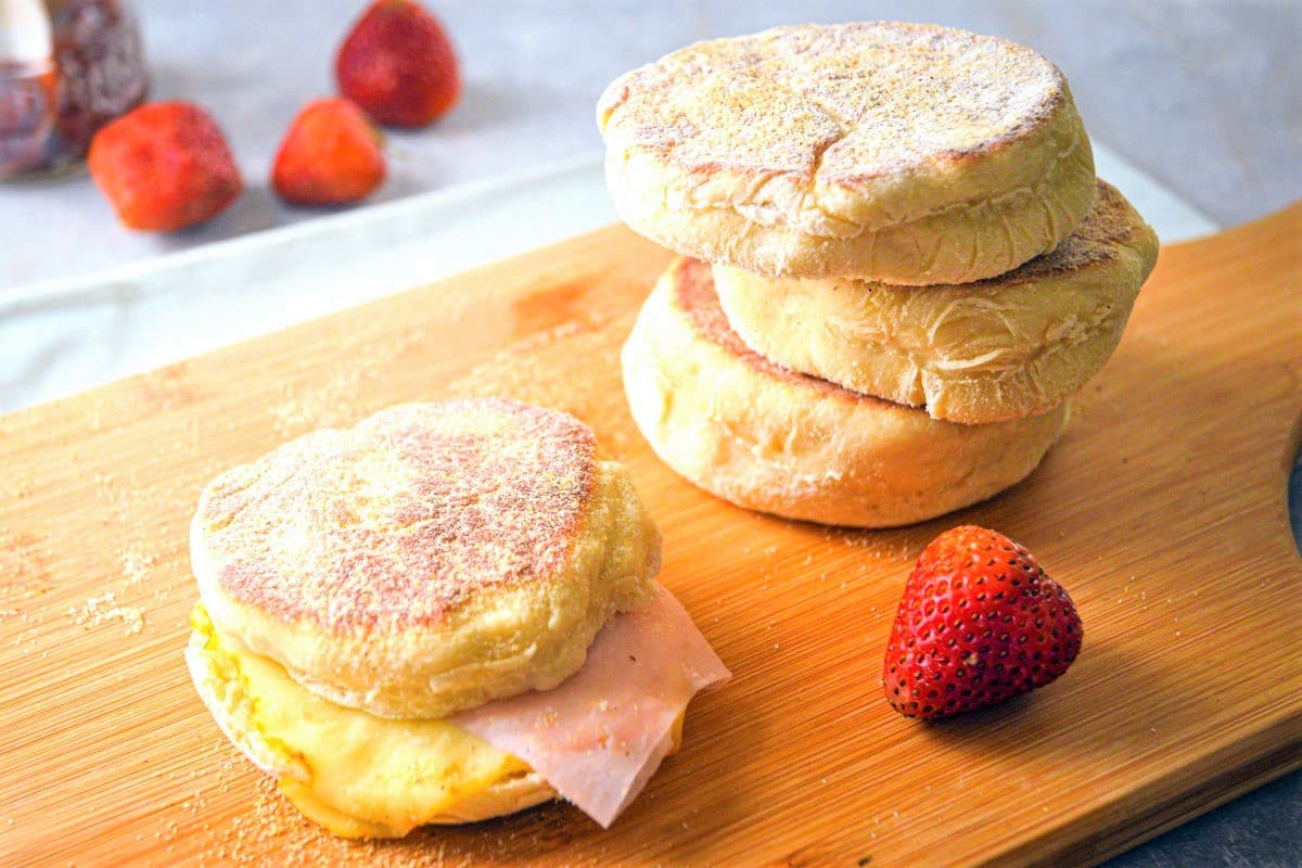 English muffins with ham and melted cheese on wooden board.