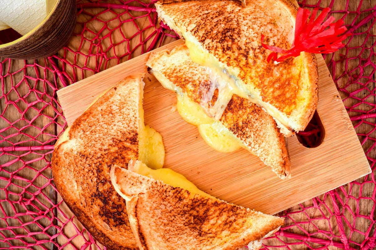 Electric skillet grilled cheese sandwiches on a cutting board. over a pink doiley.