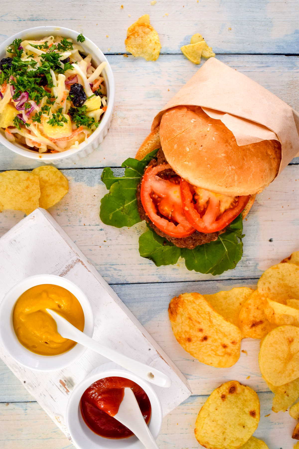 Electric Skillet Hamburgers on wooden background with salad and condiments on the side.