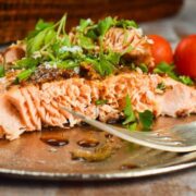 Wild salmon with fresh parsley and tomatoes on a plate with a fork.