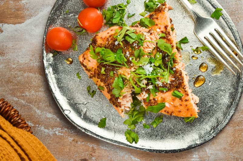 Wild salmon with fresh parsley and tomatoes on a plate with a fork.