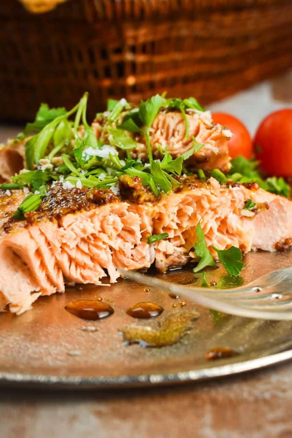 Wild salmon with fresh parsley and tomatoes on a plate with a fork.