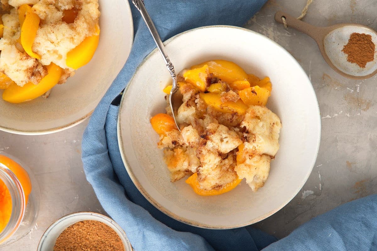 Peach cobbler in bowls with a spoon.