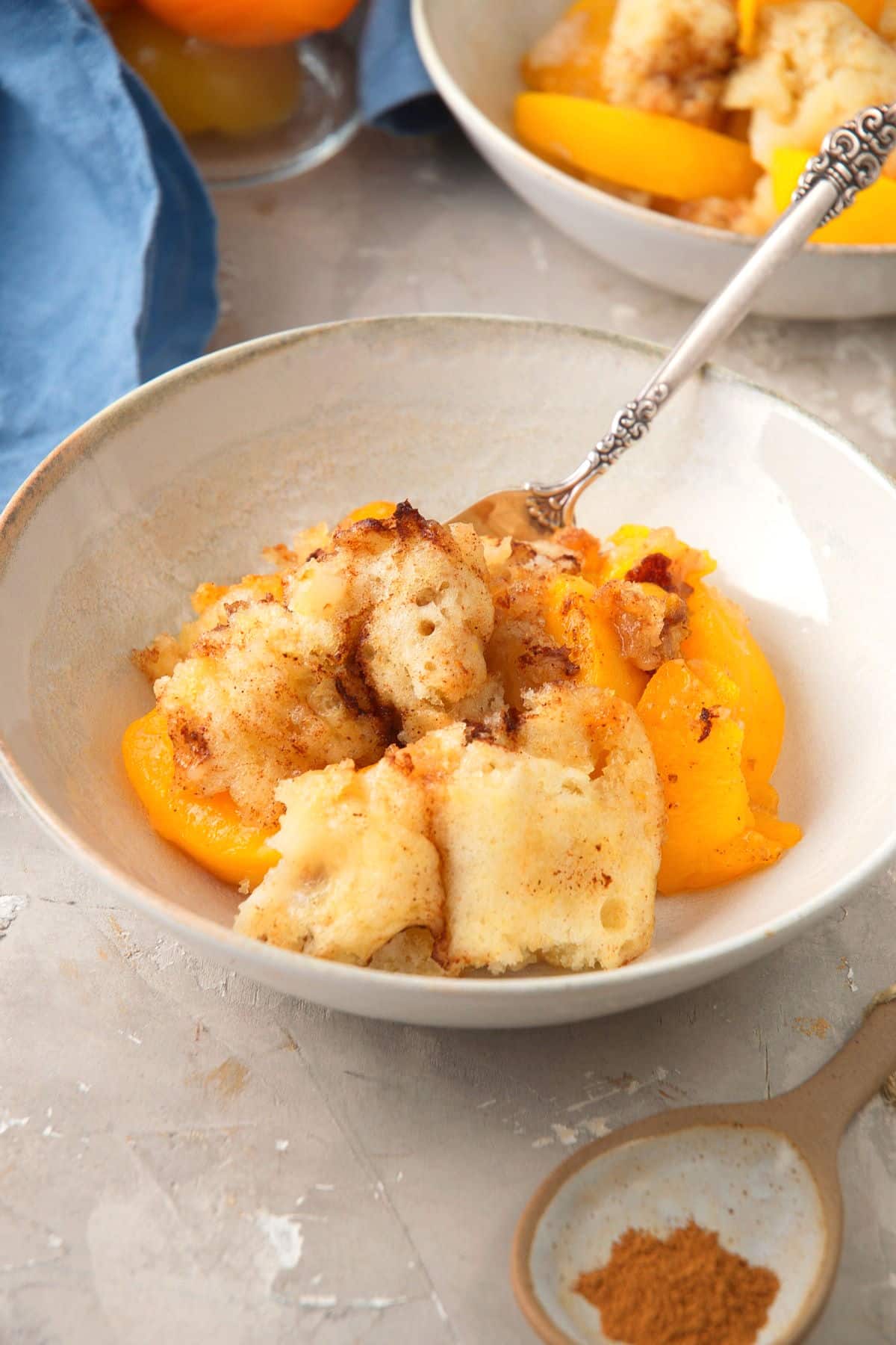 Peach cobbler in a bowl with a spoon.