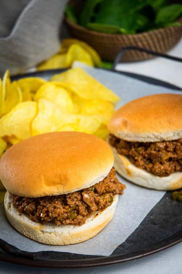 Sloppy Joes on a serving dish with chips and spinach on the side.