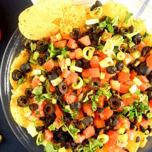 Veggie nachos on a clear glass plate.