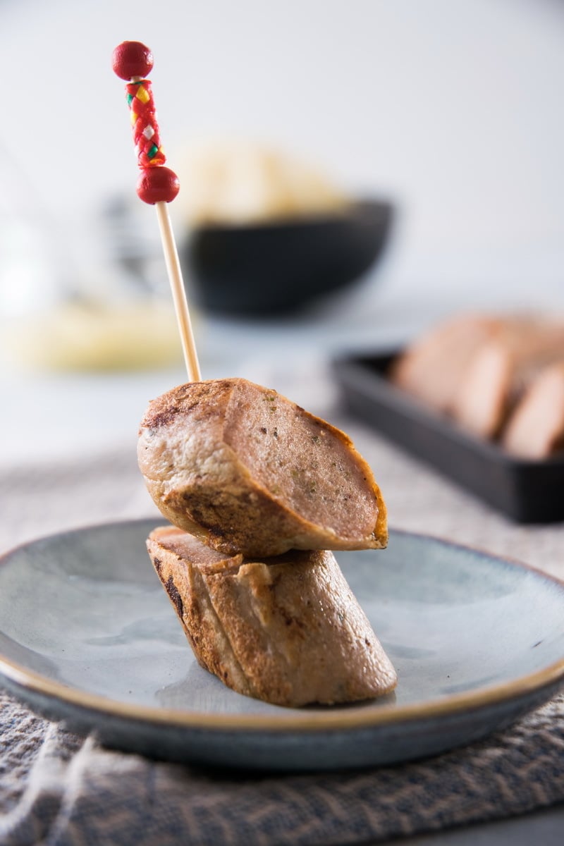 Sausage slices on a toothpick on a plate.