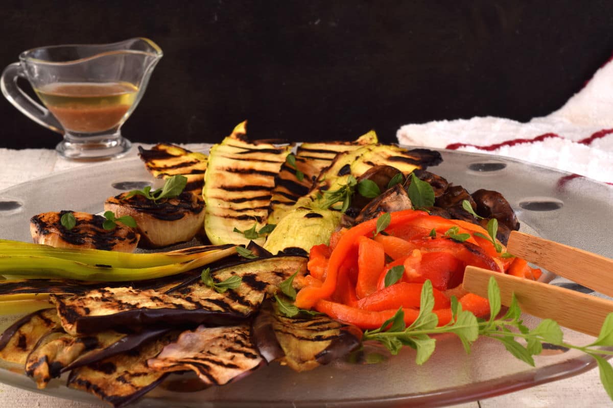 Escalivada on a plate, with dressing on black background.