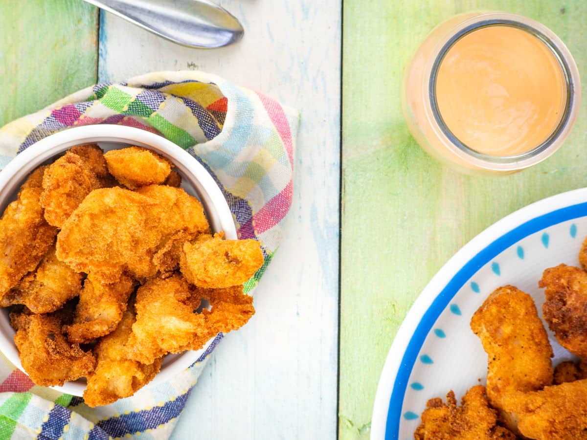 Fish sticks in a white ramekin and sweet mayo dip in the side.