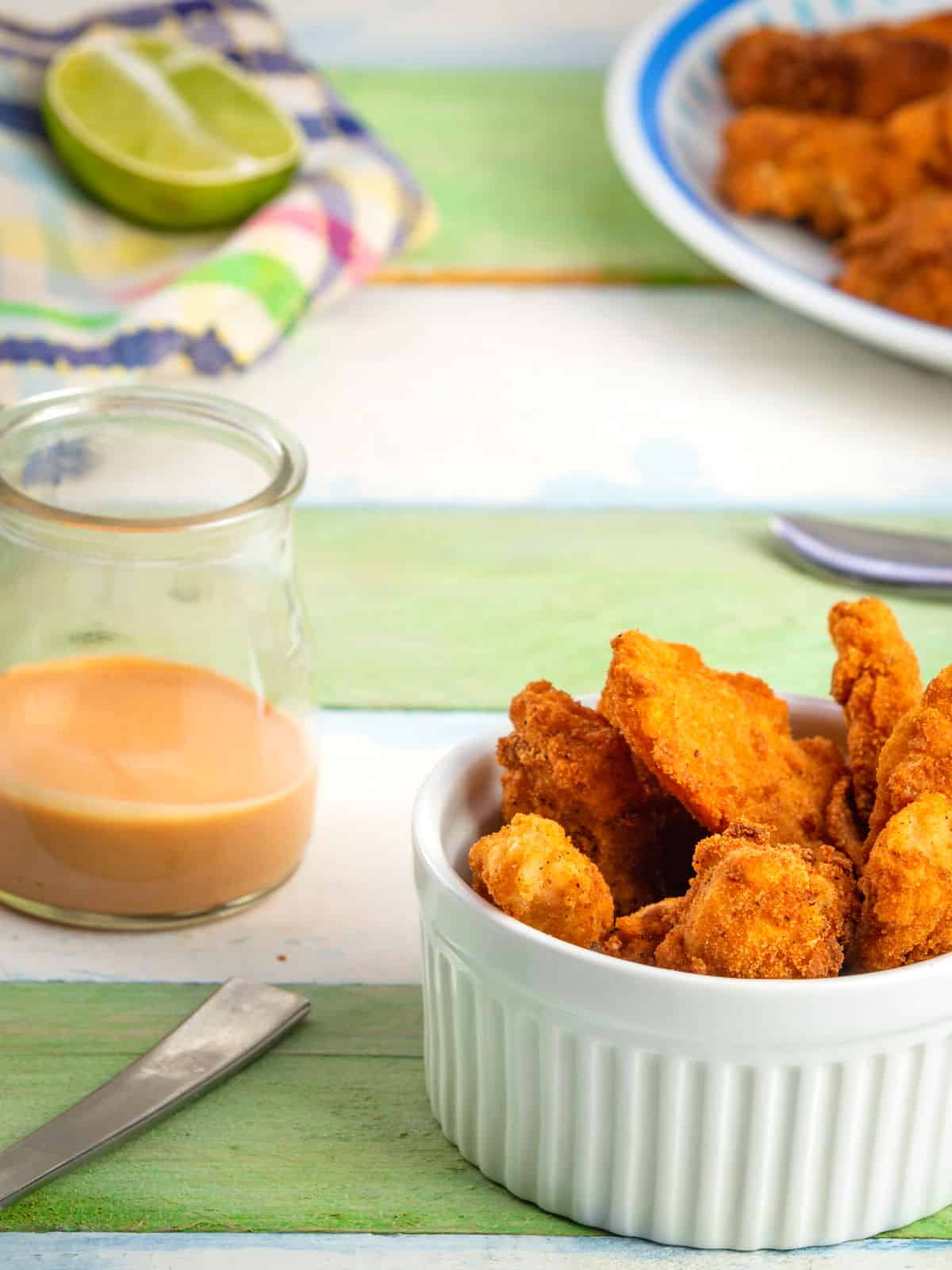 Fish sticks in a white ramekin, green and white wooden background.