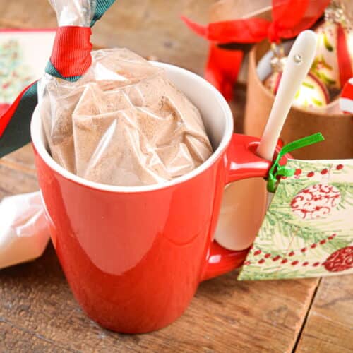 Chocolate cake ingredients in a red mug with Christmas decorations on brown, wooden background.