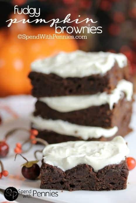 Stacked pumpkin brownies with white frosting.