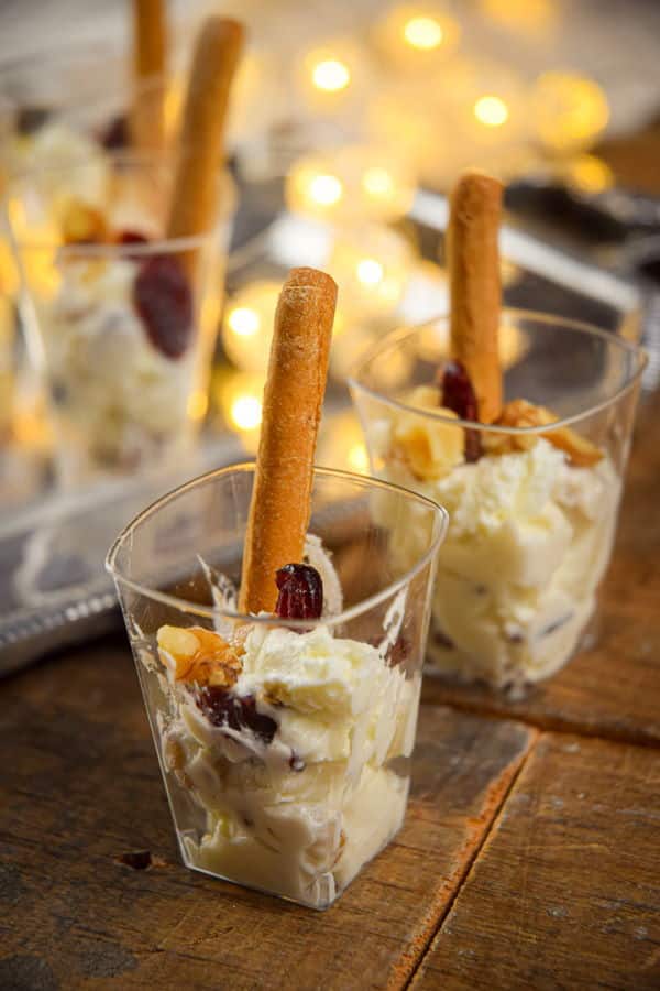 Nutty cranberry goat cheese shots with crispy breadsticks, wooden background and Christmas lights.