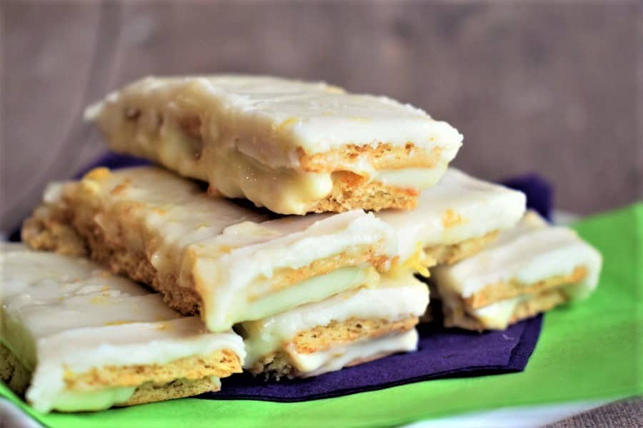 Graham wafer lemon bars on a white plate with purple and green napkins.