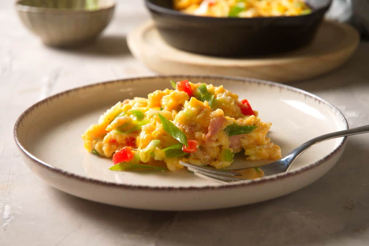 Scrambled eggs on white plate with a fork.