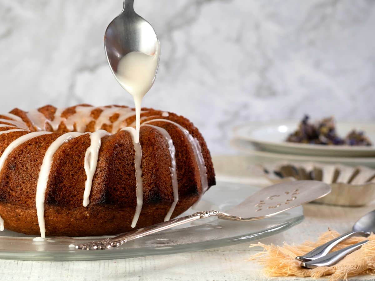 Icing drizzling from spoon over grapefruit cake.
