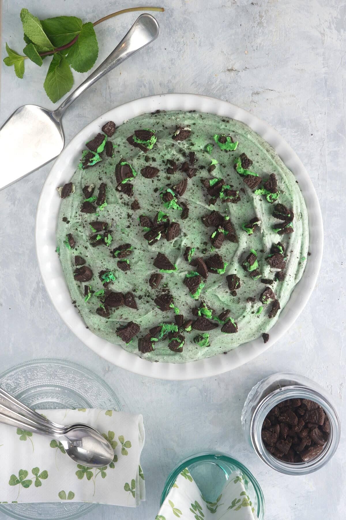 Grasshopper pie in ceramic pie plate with crushed Oreo cookies on the side.