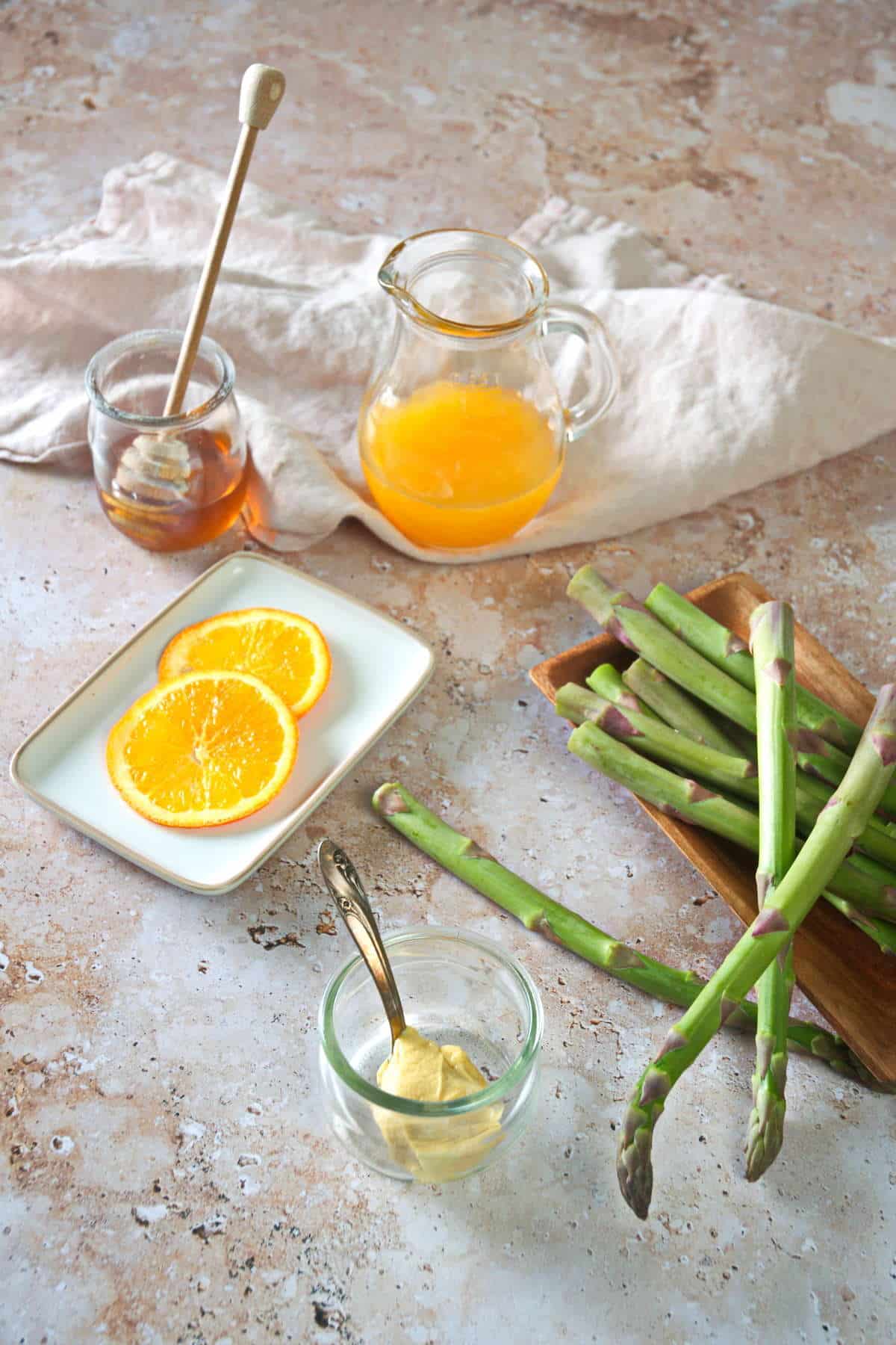 Fresh asparagus, orange slices and honey prepped on marble background.