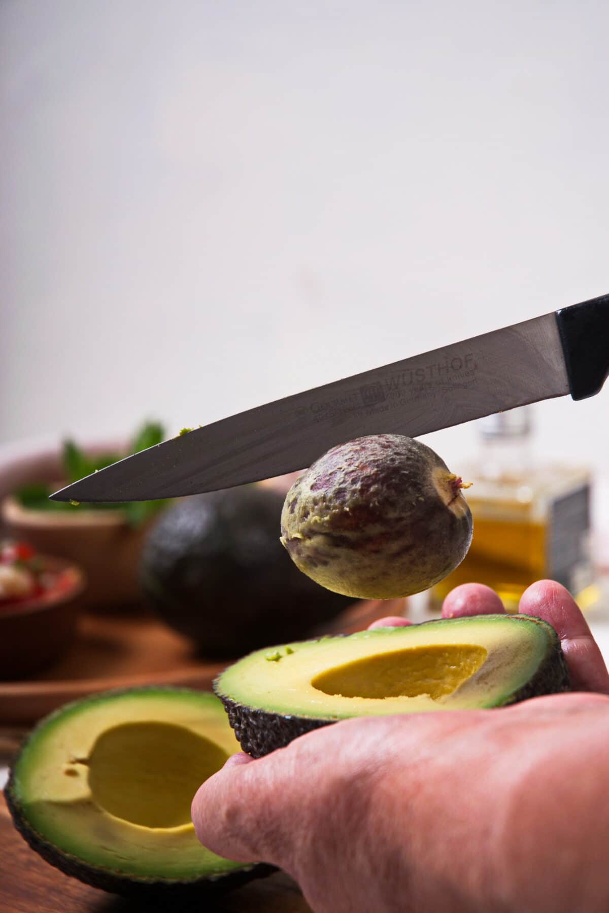 Avocado sliced up, knife in pit.