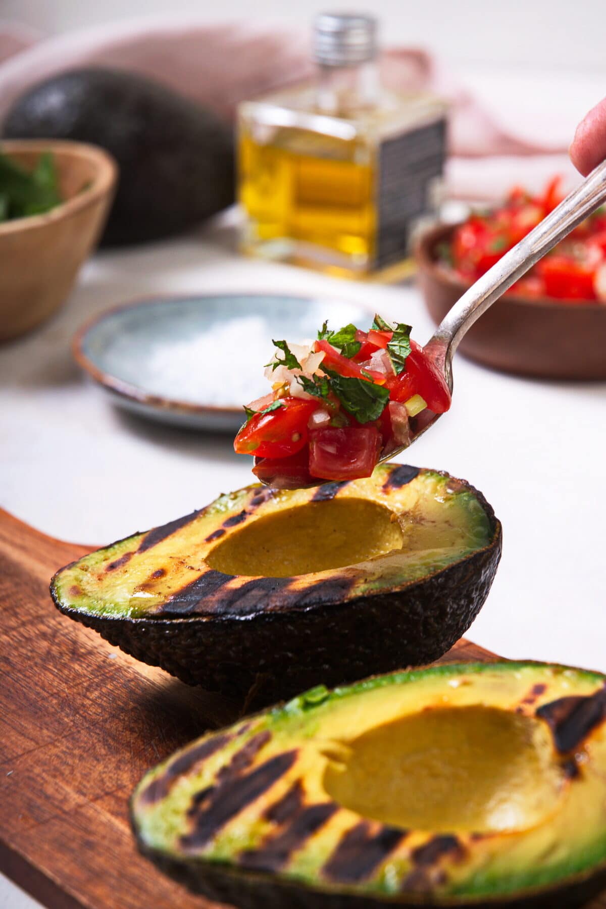 Grilled avocado halves with a spoon of pico de gallo.