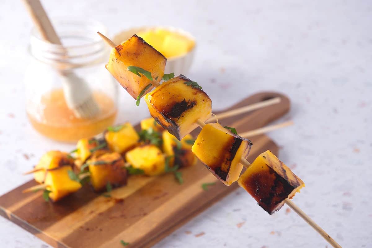 Grilled mango skewer on light background.