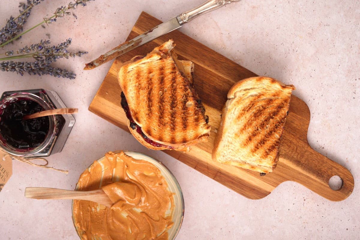 Grilled PBJ sandwiches on cutting board with a butter knife.