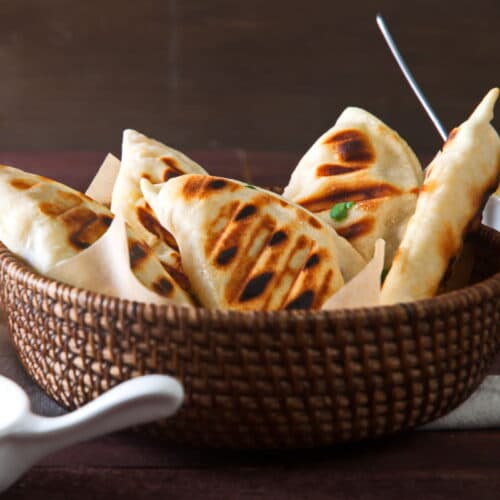 Grilled pierogies in basket on wooden background.