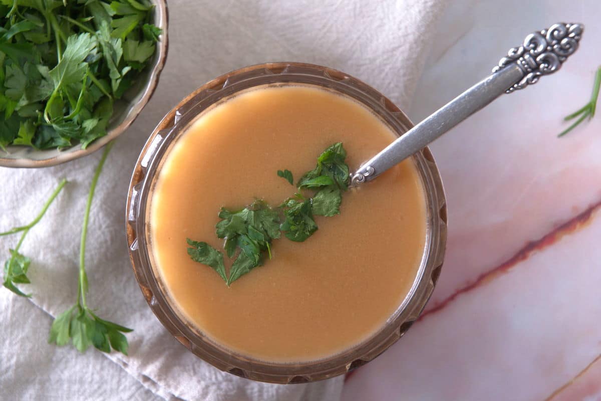 Ham gravy in a bowl with freshly chopped parsley - top view.