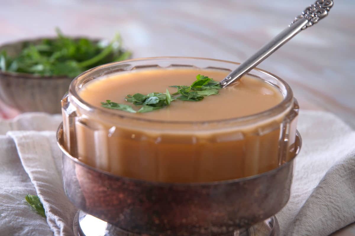 Ham gravy in a bowl with freshly chopped parsley.