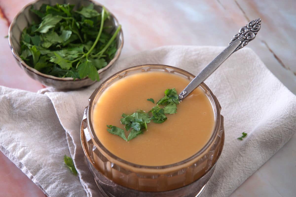 Ham gravy in a bowl with freshly chopped parsley.