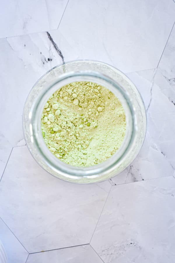 Homemade matcha latte mix in a jar, marble background.