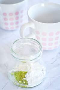 Vegan matcha latte powder in small jar unmixed.