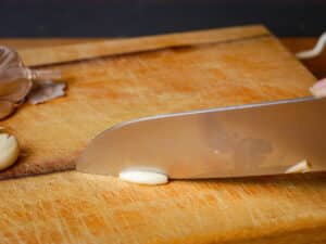 Chef's knife slicing garlic.