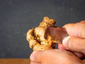Ginger root in hands with a spoon.