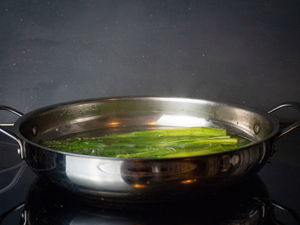 Asparagus cooking in frying pan.