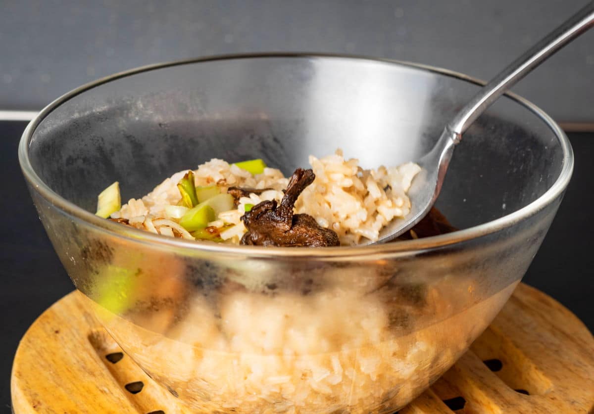 Brown rice with mushrooms in clear bowl.