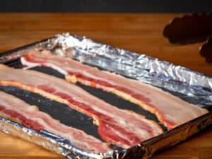 Raw bacon on foil-lined sheet pan.