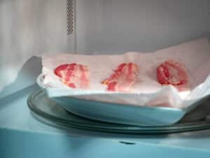 Raw bacon on paper towel in microwave.