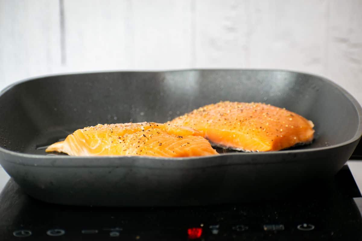 2 salmon fillets in pan, cooking.