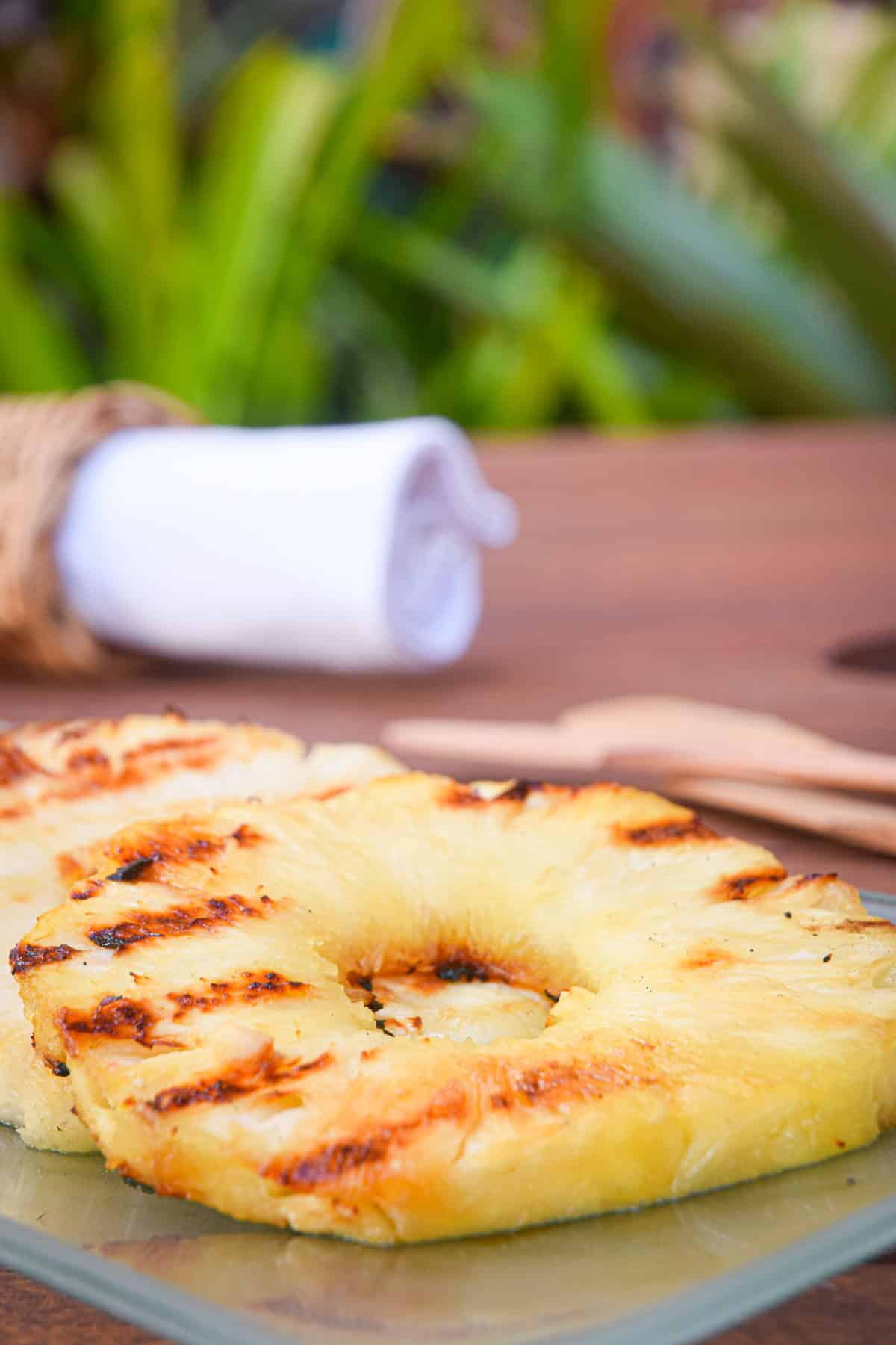 Grilled pineapple slices on glass serving dish.