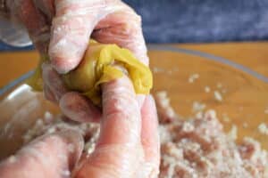 Cabbage roll being rolled up with gloved hands.