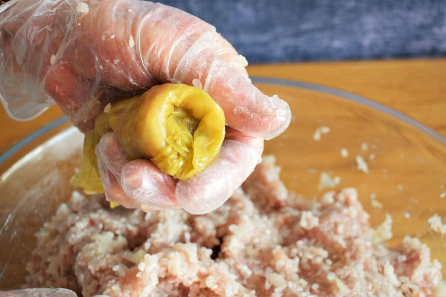 Cabbage roll being rolled up with gloved hands.