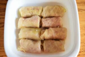 Cabbage rolls in a casserole dish, wooden background.