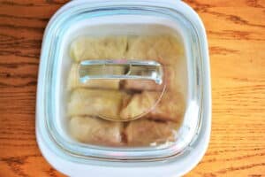 Cabbage rolls in a casserole dish with the lid on, wooden background.