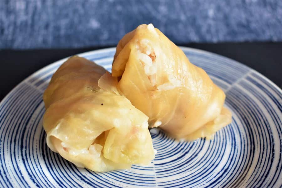 Cabbage rolls on a blue and white plate, blue background.