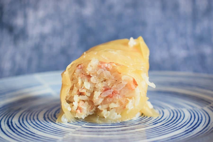 Open cabbage roll on a blue and white plate, blue background.